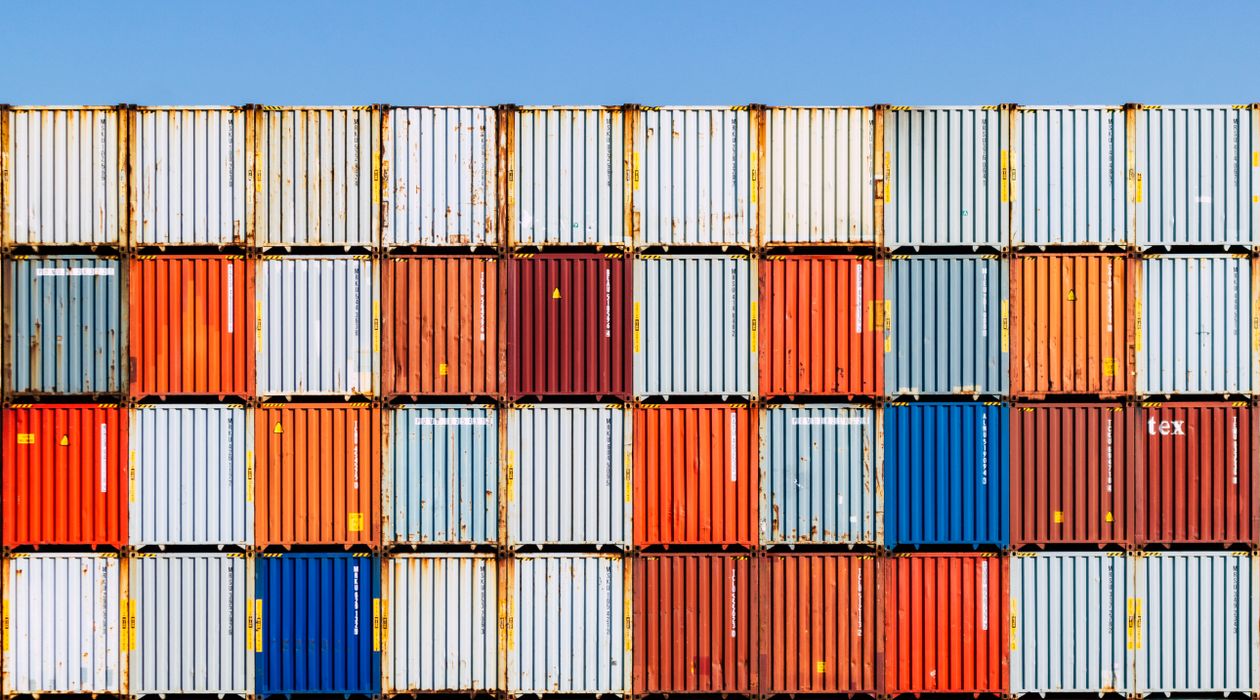 Real shipping containers stacked in a yard beneath a blue sky
